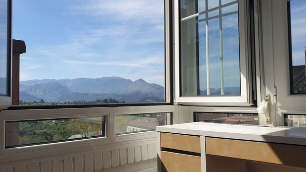 Une pièce avec vue sur les montagnes, grâce à de grandes fenêtres, un radiateur et un bureau en bois.