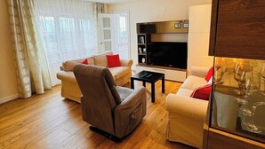Un salon moderne avec un canapé, un fauteuil et un téléviseur à écran plat.