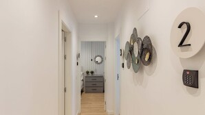 A hallway with a wooden floor, a door on the left, a wall-mounted number '2' sign, and a wall-mounted security keypad.