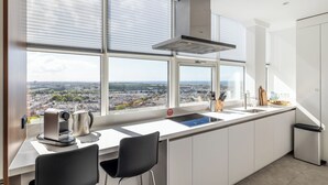 A modern kitchen with a large window, a built-in stove, and a view of the city. - BizStay Toren van Oud (The Hague)