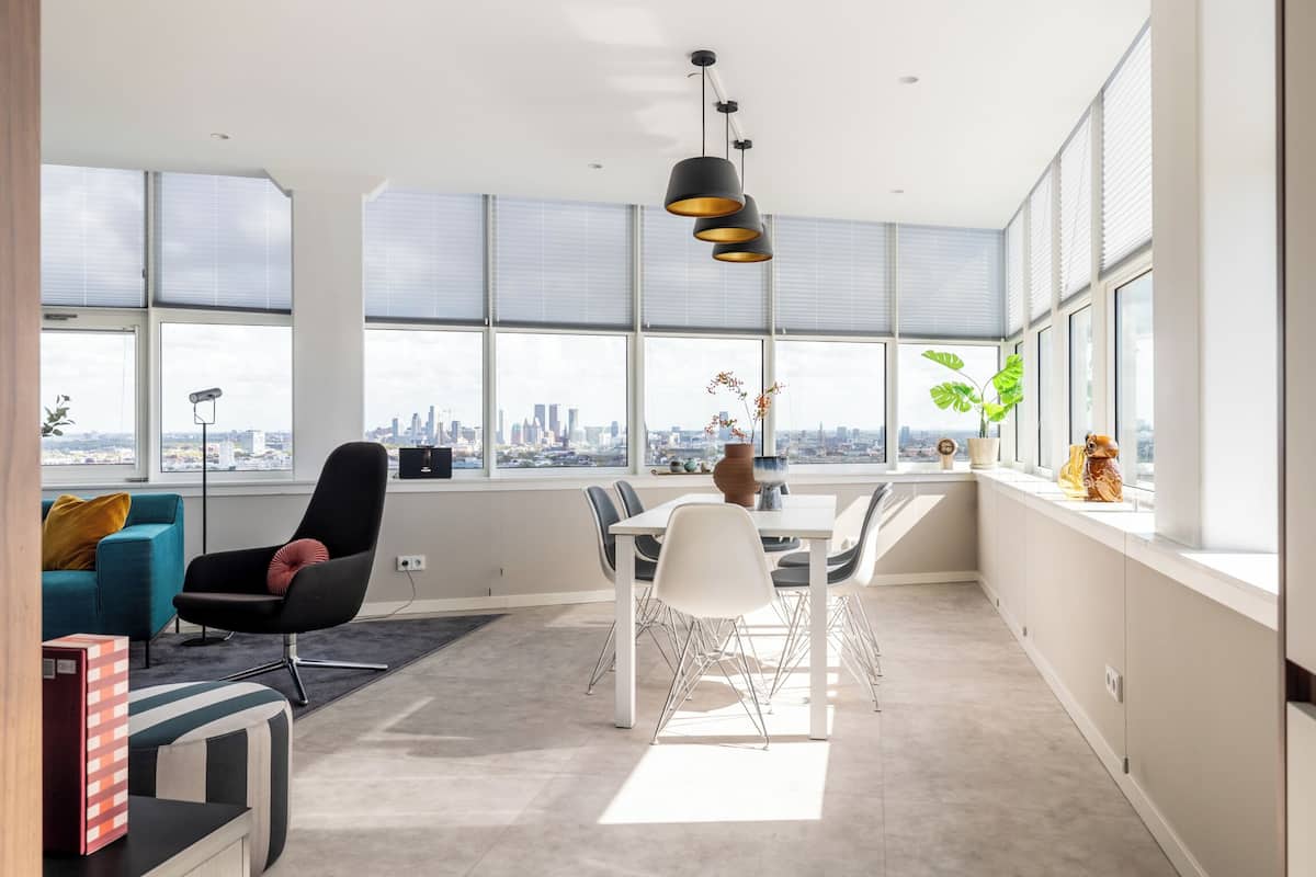 Een moderne kantoorruimte met een grote tafel, stoelen en een stadszicht door grote ramen.
