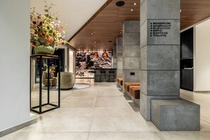 Un hall d’hôtel moderne comprenant un comptoir d’accueil, un espace salon et un mur orné de panneaux d’orientation.