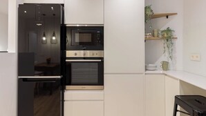Una cocina moderna con refrigerador integrado, microondas, horno y encimera negra.