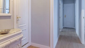 A hallway with a light-colored wooden floor, white walls, and a white door at the end. - AH Apartment Urban Lena VUT-6048-AS (Pola de Lena)