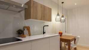 Una cocina moderna con armarios blancos, un grifo negro y una mesa de comedor de madera con sillas.