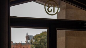 Een zicht door een deur, met een metalen hendel en een rond logo erboven.