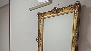 A dark wooden console table with a marble top, a gold-framed mirror, and a vase with purple flowers. - Apartment AH2 by Gestión House. VUT-6514-AS (Noreña)