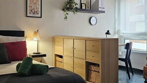 A bedroom with a bed, bedside lamp, wooden wardrobe, wall art, and a clock. - Apartment AH2 by Gestión House. VUT-6514-AS (Noreña)