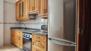 A kitchen with wooden cabinets, a stainless steel refrigerator, a microwave, an oven, and a granite countertop. - Apartment AH2 by Gestión House. VUT-6514-AS (Noreña)