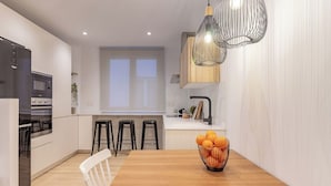 Una cocina moderna con armarios blancos, una mesa de comedor de madera y una encimera negra.