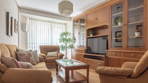 Un salon comprenant un ensemble de canapés, une table basse, un téléviseur et des meubles de rangement en bois.