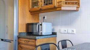 A kitchen with wooden cabinets, a stainless steel refrigerator, a microwave, and a granite countertop. - Asturias holidays by Gestión house 3 (Noreña)