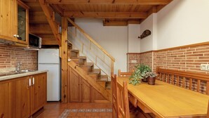 Eine Küche mit Holzausstattung, einer Ziegelrückwand, einem Holzessttisch und einer Treppe.