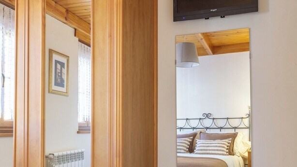 Ein Schlafzimmer mit Holzwandverkleidung, einem Bett mit Kopfteil, einem angebrachten Fernseher und einem gerahmten Bild an der Wand.