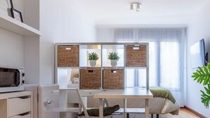 Eine moderne Küche mit weißen Schränken, einer eingebauten Mikrowelle, einem Esstisch mit Stühlen und einem großen Fenster mit Vorhängen.