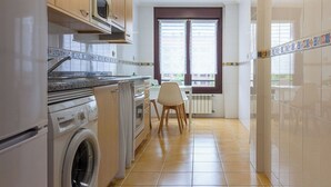 Eine kompakte Küche mit Waschmaschine, Backofen, Mikrowelle und einer Essecke mit Stuhl und Tisch.