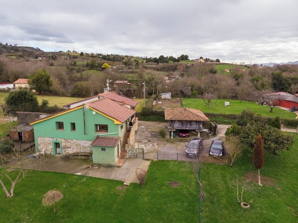 A rural house with a green exterior and a red roof, surrounded by a grassy yard and a small garden. - AH Townhouse "La Casina de Cués". VV-1762-AS (Asturias)