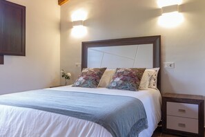 A neatly made bed with a headboard, two bedside lamps, a nightstand with drawers, and a wall-mounted light fixture. - AH Townhouse "La Casina de Cués". VV-1762-AS (Asturias)