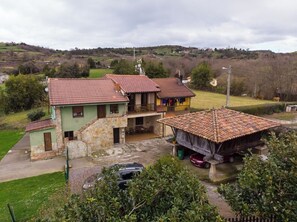 A two-story house with a tiled roof, a balcony, and a small attached structure with a tiled roof. - AH Townhouse "La Casina de Cués". VV-1762-AS (Asturias)