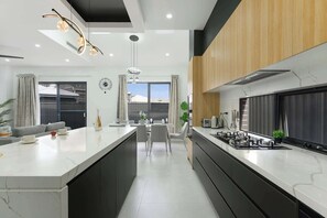 A modern kitchen with a central island, black cabinets, and stainless steel appliances.