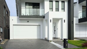 A modern two-story house with a white facade, a garage, and a balcony.