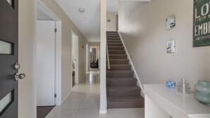 Un pasillo con una escalera alfombrada, una puerta blanca y una pared con un letrero que dice 'Cada momento es una oportunidad'.