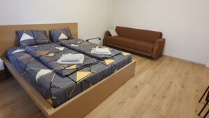 A bed with a geometric patterned bedspread, a brown sofa, and a wooden floor.