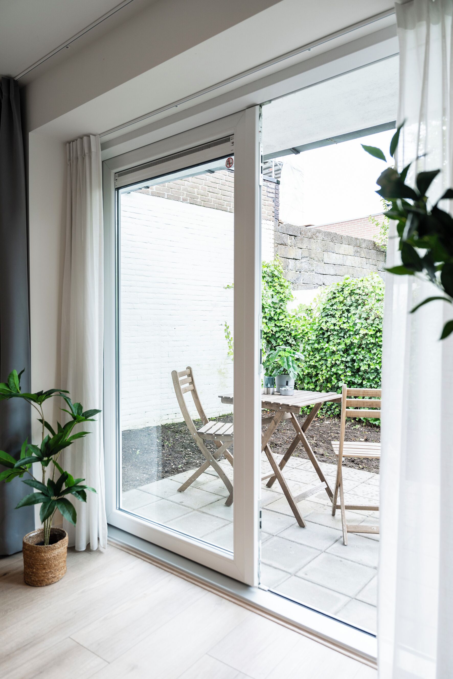 A room with a sliding glass door leading to an outdoor patio with a table and chairs.