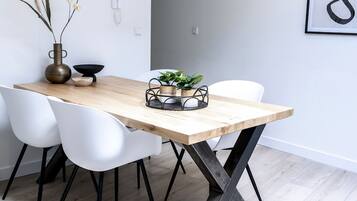 Una mesa de comedor con tapa de madera y patas de metal negro, rodeada de sillas blancas.