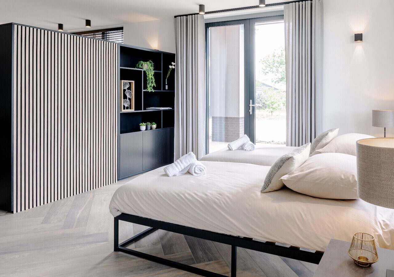 Ein modernes Schlafzimmer mit einem großen Bett, einem eingebauten Kleiderschrank und Blick ins Freie.