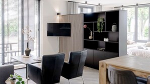 A modern living room with a black sofa, a wooden coffee table, and a black TV stand with shelves.