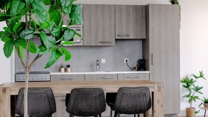 A modern kitchen with a wooden island, grey cabinets, and bar stools.