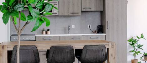 A modern kitchen with a wooden island, grey cabinets, and bar stools.