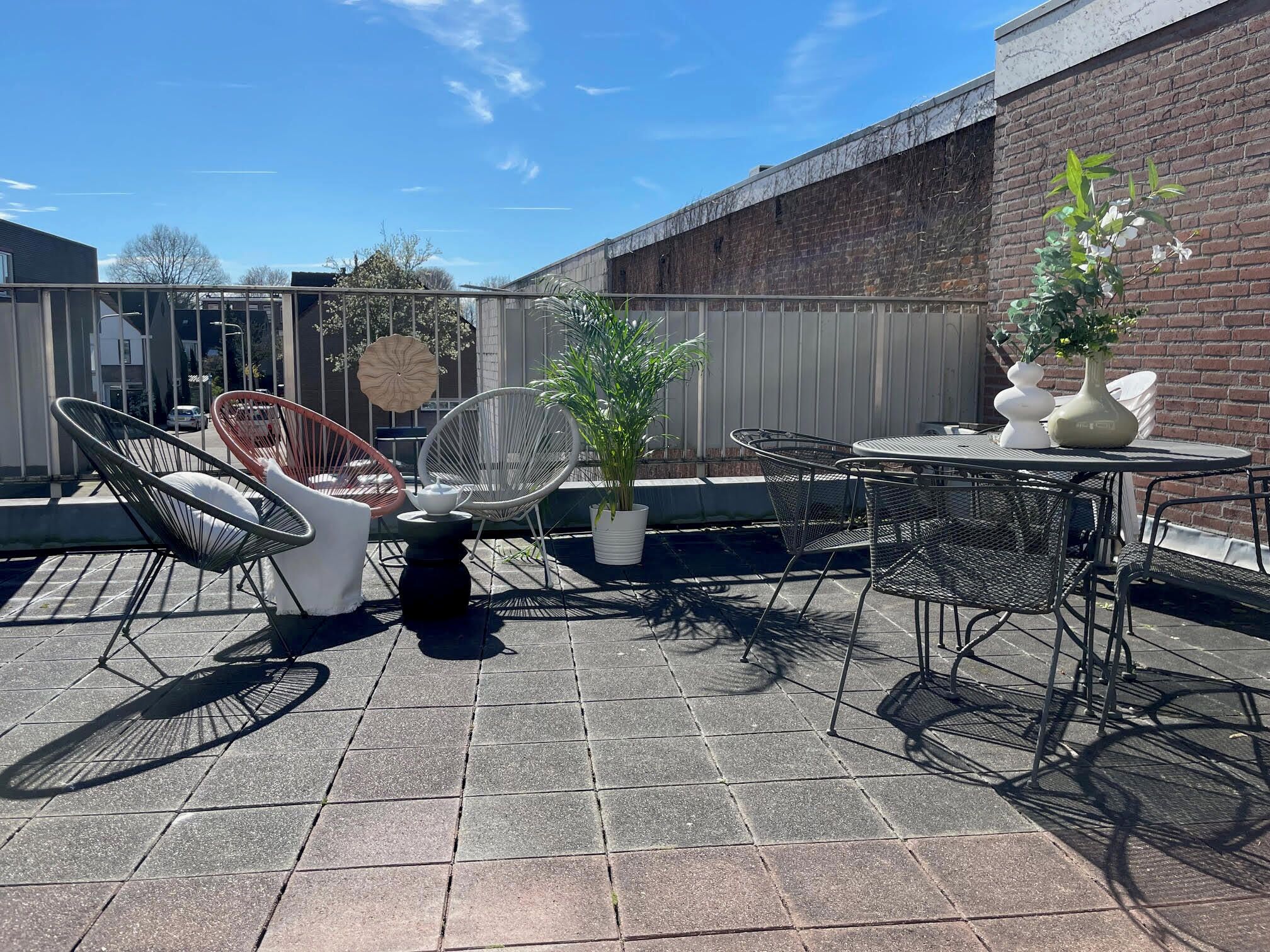An outdoor patio with metal chairs, a round table, and potted plants.