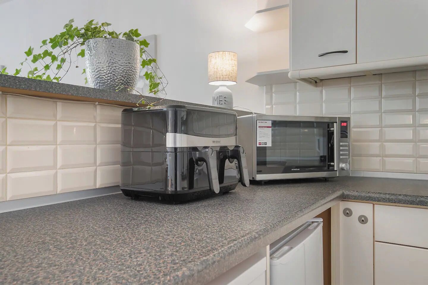 A kitchen with a coffee maker, microwave, and a plant on the counter.
