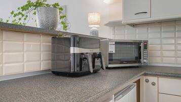 A kitchen with a coffee maker, microwave, and a plant on the counter.