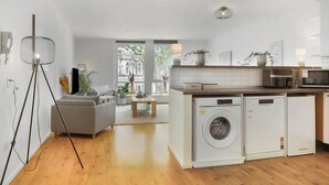 Una cucina moderna con lavatrice e asciugatrice integrate, un'area pranzo con tavolo e sedie, e un'ampia finestra con vista sulla città.