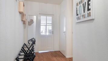 Un couloir avec un plancher en bois, une porte blanche et un panneau fixé au mur.