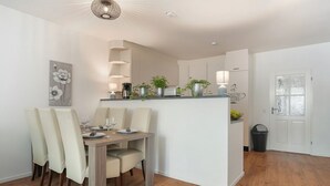 Una cucina compatta con zona pranzo, caratterizzata da un'isola centrale, mobili bianchi e un tappeto grigio.