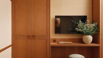A wooden wardrobe with a flat-screen TV mounted above it, a vase with flowers, and a book titled "Paris" on a shelf.