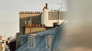 A view of a building with a sloped roof and a balcony with a metal railing. - HIGHSTAY Maisons - Vintimille (Paris)