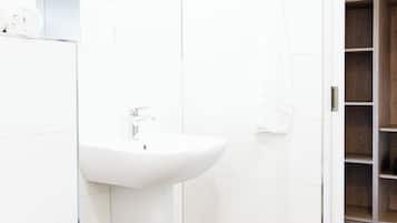 Un baño moderno con lavamanos blanco, inodoro y zona de ducha.