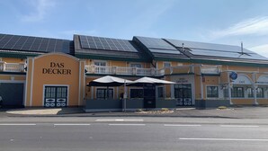 A building with a yellow facade, solar panels, and a sign reading "DAS DECKER". - DAS DECKER (Paldau)