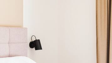Un dormitorio con cama, cabecera, lámpara de pared y cortina.