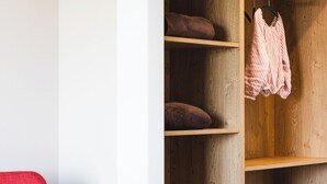 A red chair and a wooden wardrobe with multiple shelves. - DAS DECKER (Paldau)