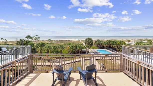 A balcony with two Adirondack chairs overlooking a pool and beach. - Coastal Aire - Gulf Front 3 bed, 4 bath! (Port St. Joe)