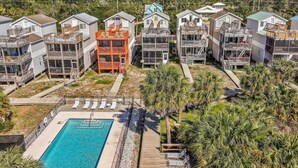 A residential area with multiple two-story houses, a swimming pool, and a small park with palm trees. - Coastal Aire - Gulf Front 3 bed, 4 bath! (Port St. Joe)