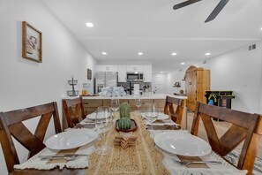 A dining area with a table set for four, a cactus centerpiece, and a kitchen in the background.