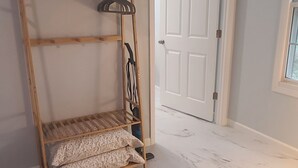 Una habitación con un banco de madera, estantes, una puerta y una ventana.
