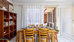Un'area pranzo con un tavolo di legno, quattro sedie e una libreria piena di libri.